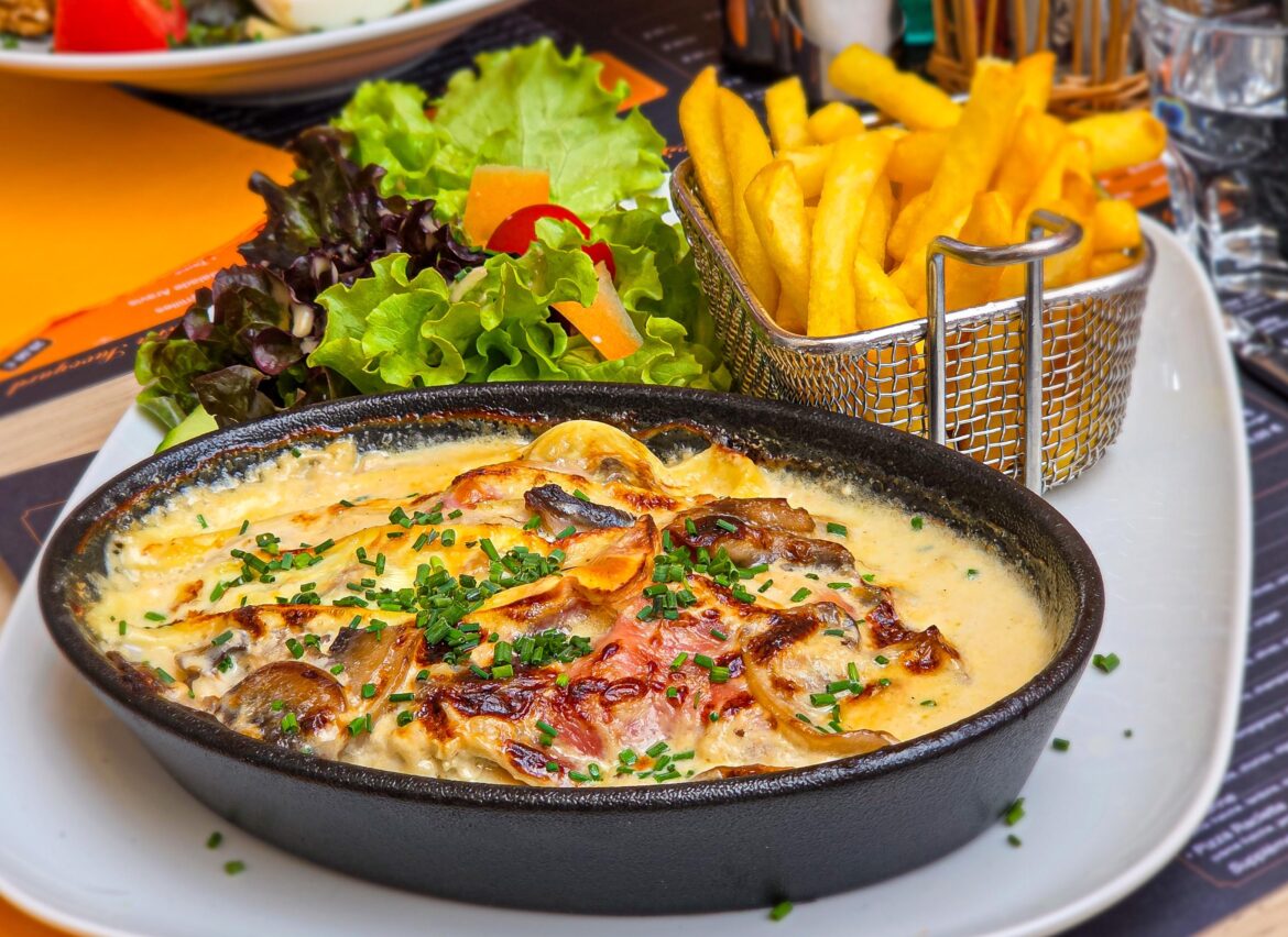 [OC]: Tartiflette made with potatoes, lardons, and onions, topped with a rich layer of cheese, and served with a green salad and French fries.