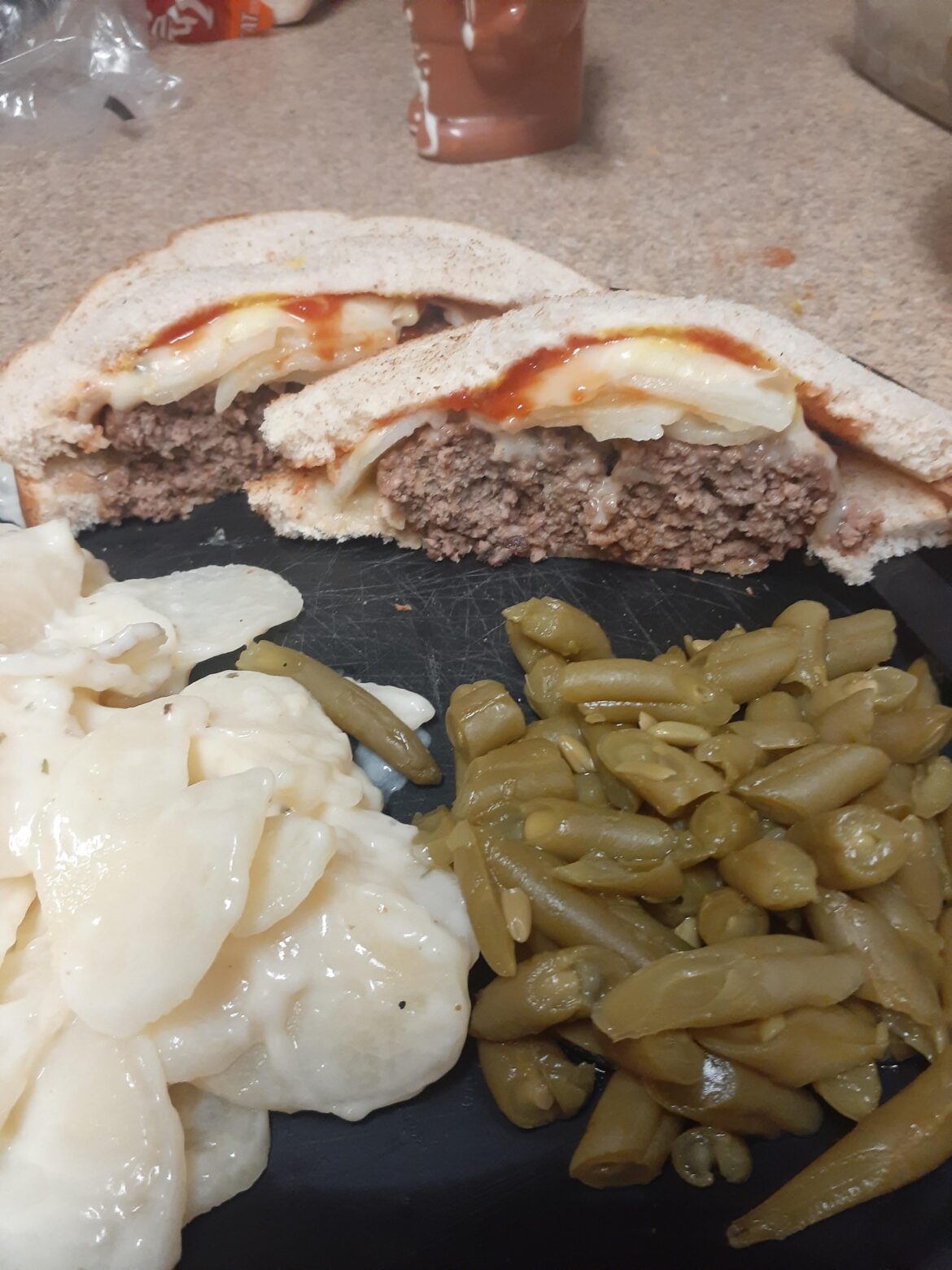 Well done chilli burger with sauteed onions, scalloped potatoes and pepper jack cheese on honey wheat bread.