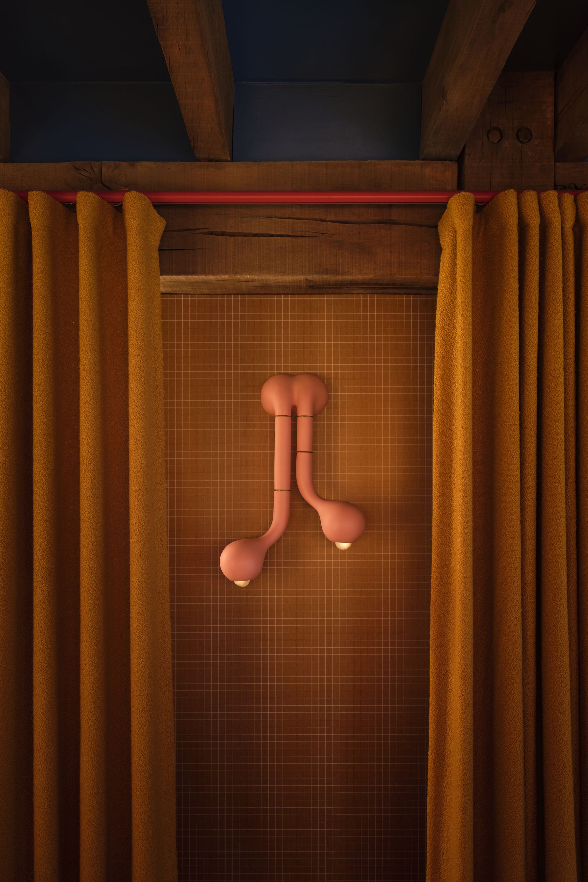 Image of a wall with yellow subway tiles and a sculptural pink scone light. There are ochre yellow curtains on a red curtain rail.