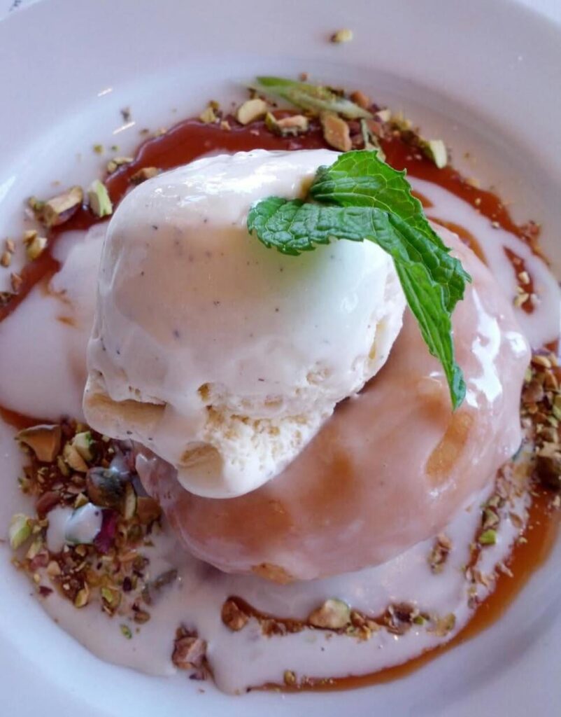 A donut filled with warm cinnamon-spiced apples, topped with vanilla ice cream