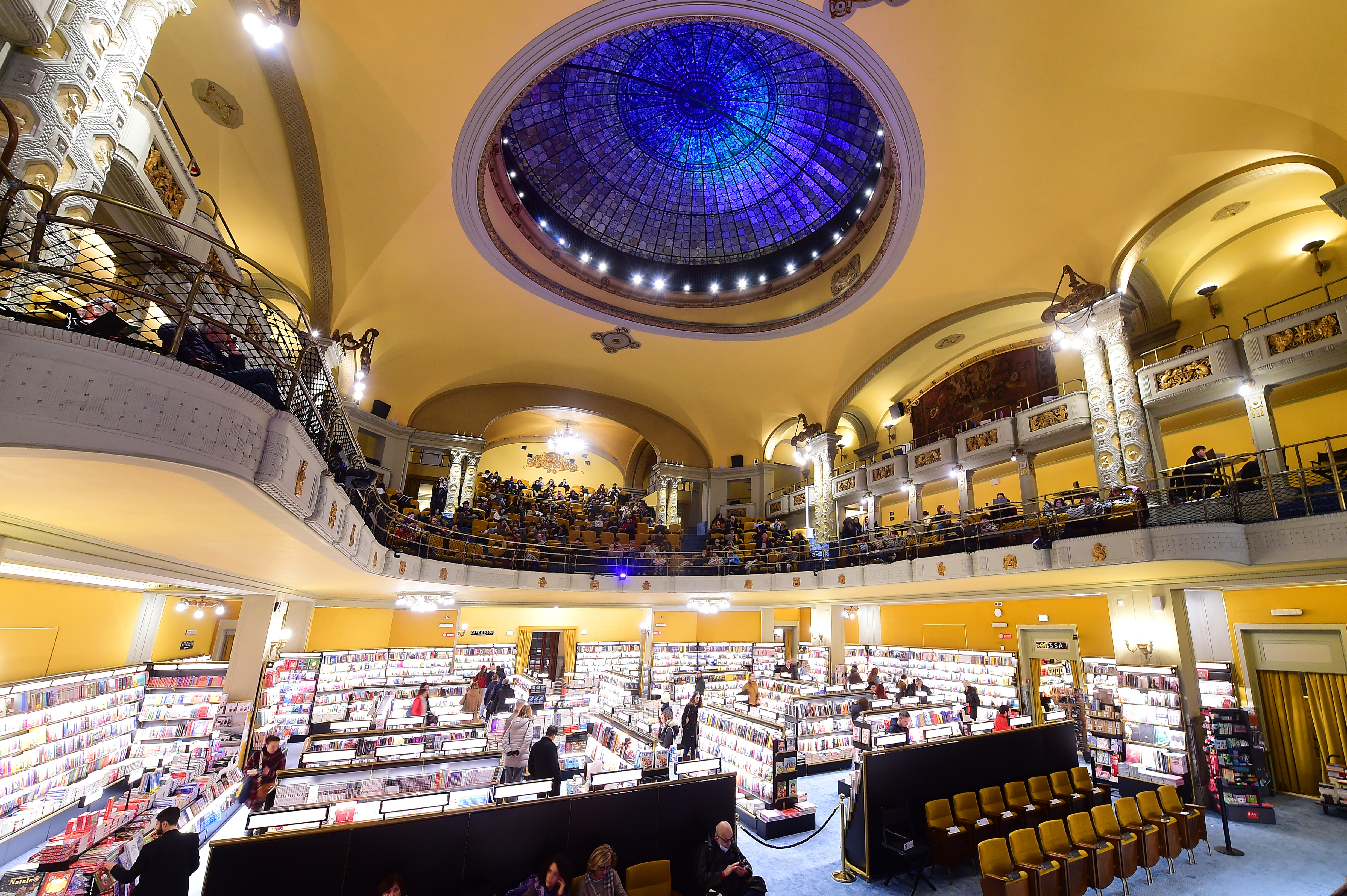 Interior of the Giunti Odeon Libreria e Cinema in Florence, Italy, with two levels of patrons and a large stained-glass dome.