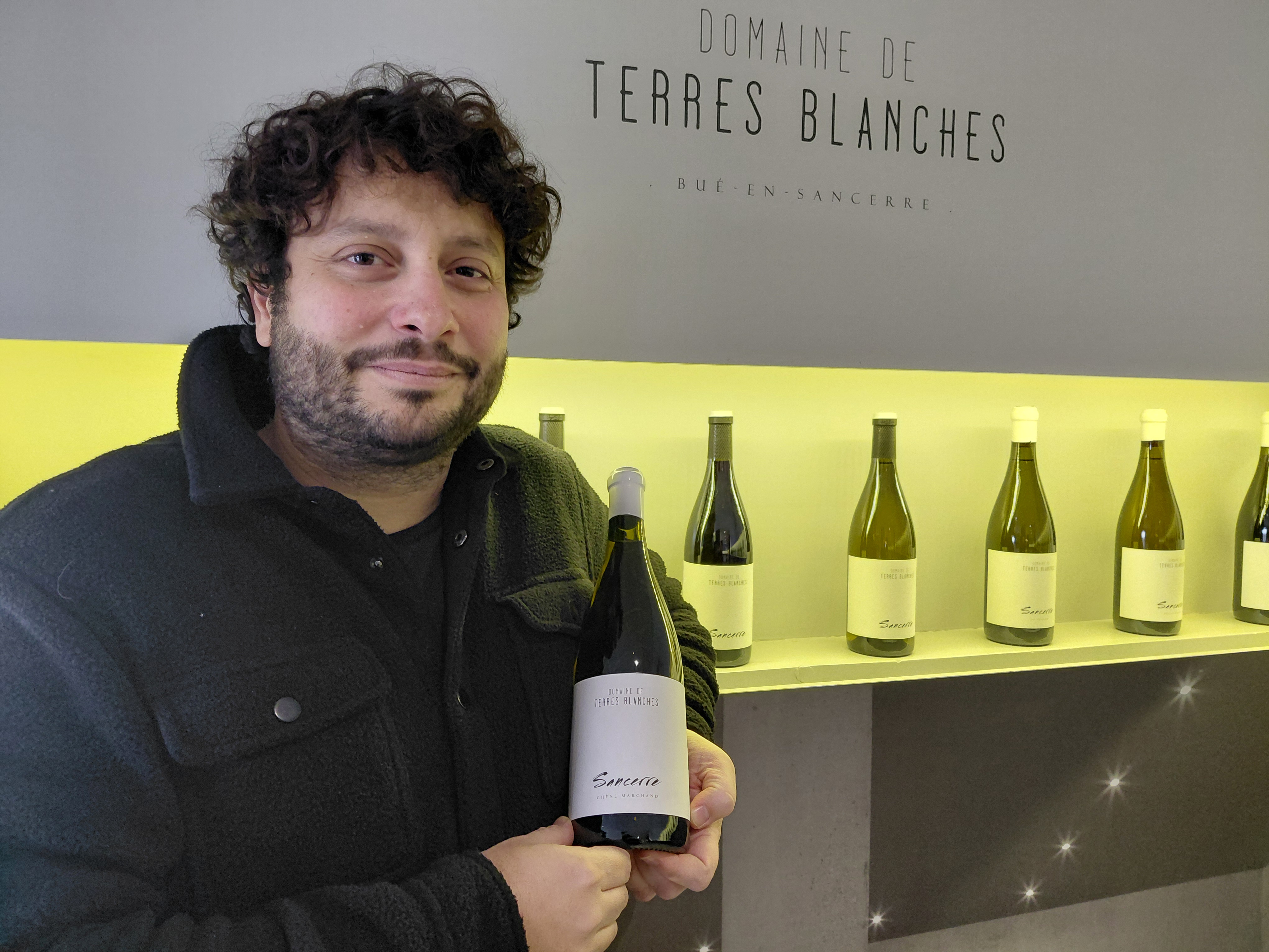 Laurent Saget of Domaine de Terres Blanches holding a bottle of Sancerre wine.