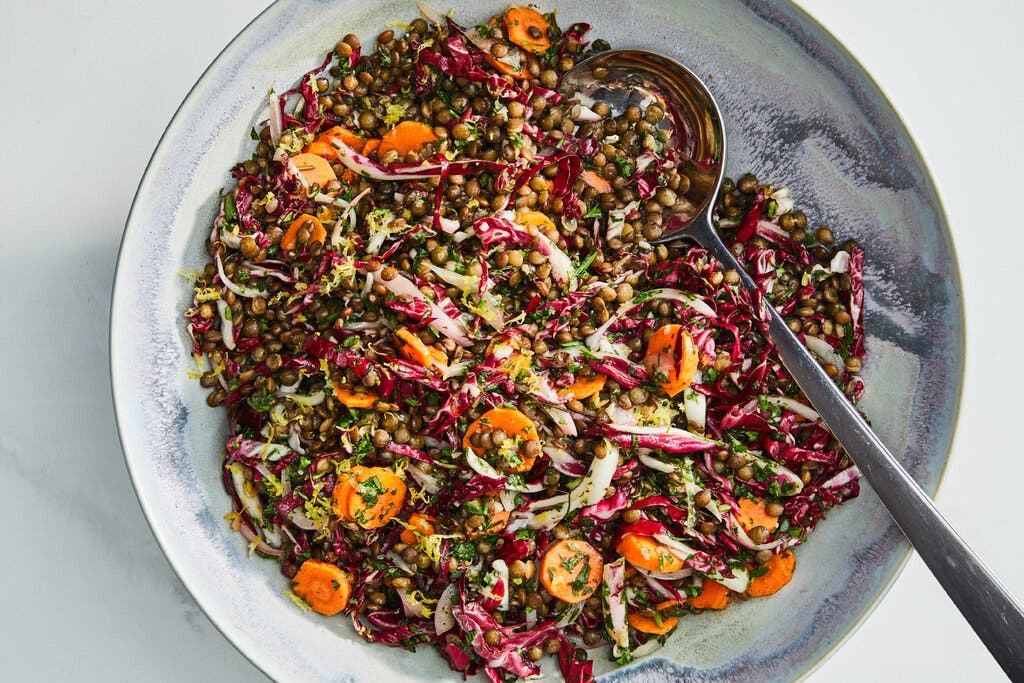 French lentil salad is shown in a marbled blue bowl with a serving spoon.