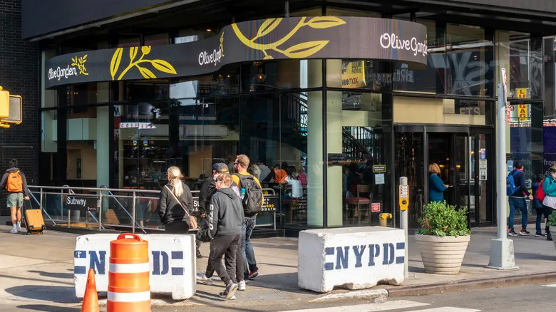 Pedestrians walk by the entrance for the Times Square Olive Garden