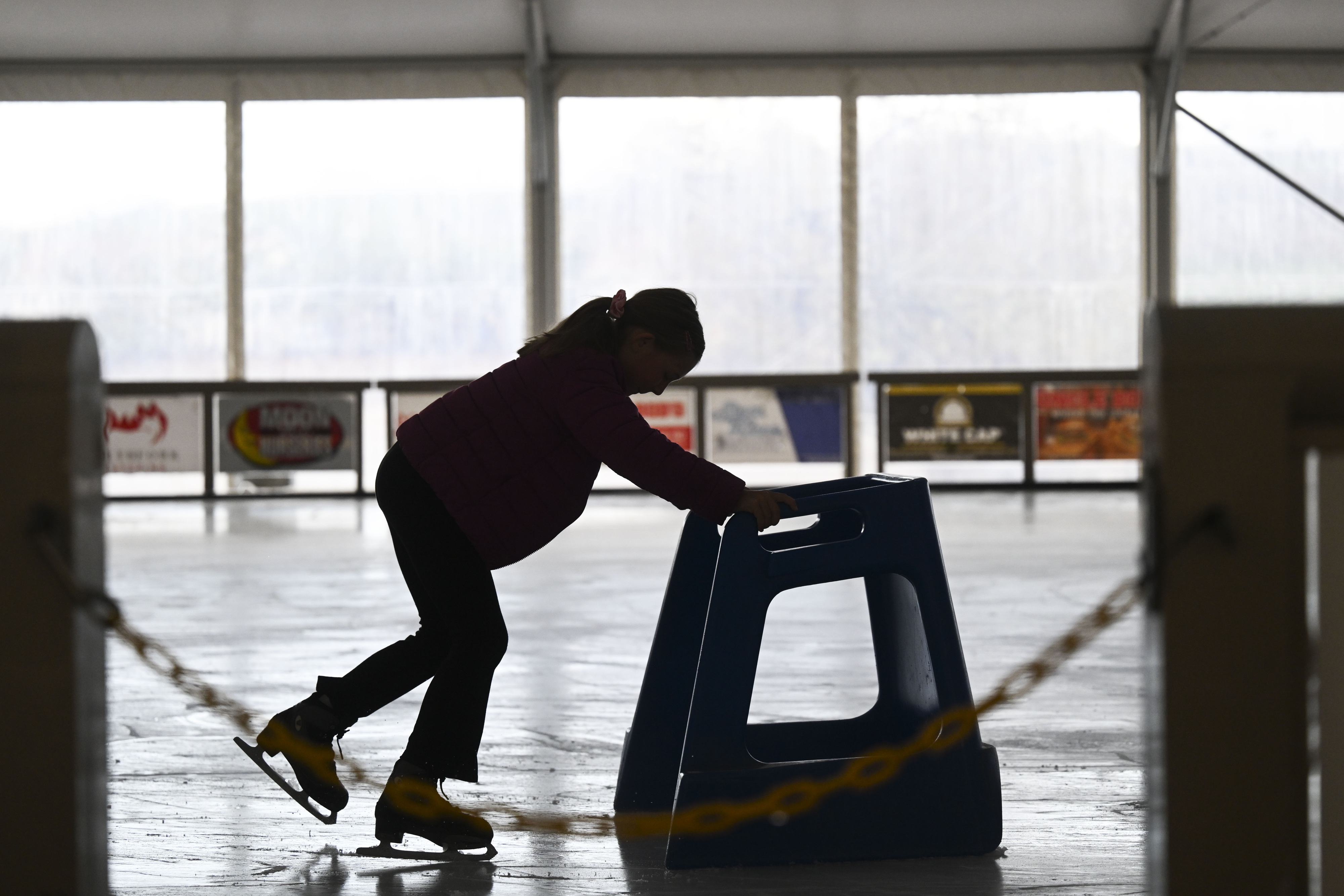 A child uses a skate helper at the ice rink...