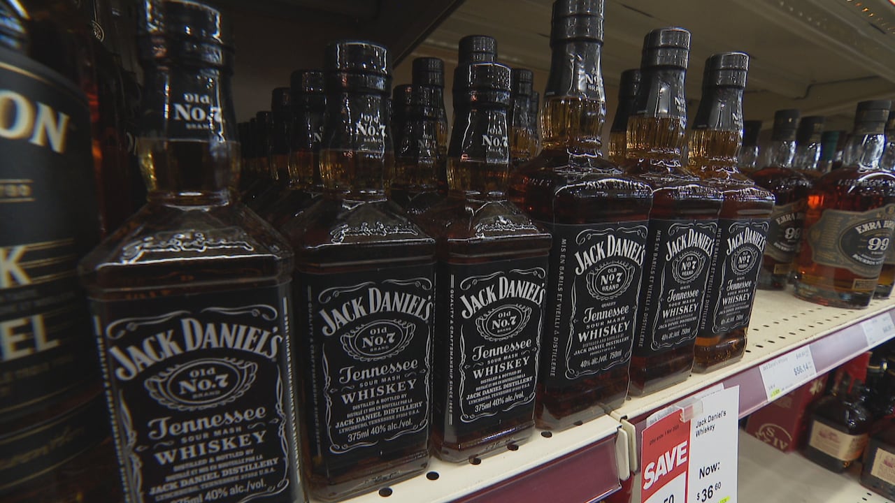 A row of Jack Daniel's bottles sit on a shelf