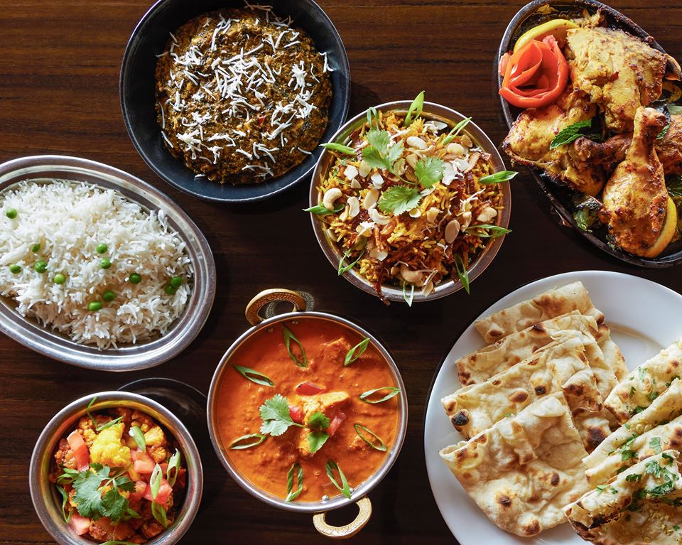 overhead shot of several indian dishes including curies, rice, and bread
