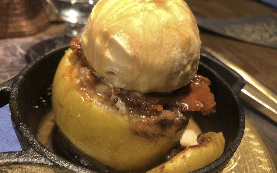 A seasonal Granny Smith baked apple dessert, featuring a hot, baked green apple stuffed with walnuts, raisins, crumble, and Ugandan vanilla custard cream, topped off with gelato and caramel sauce at Carvaan in Shibuya, Tokyo.
