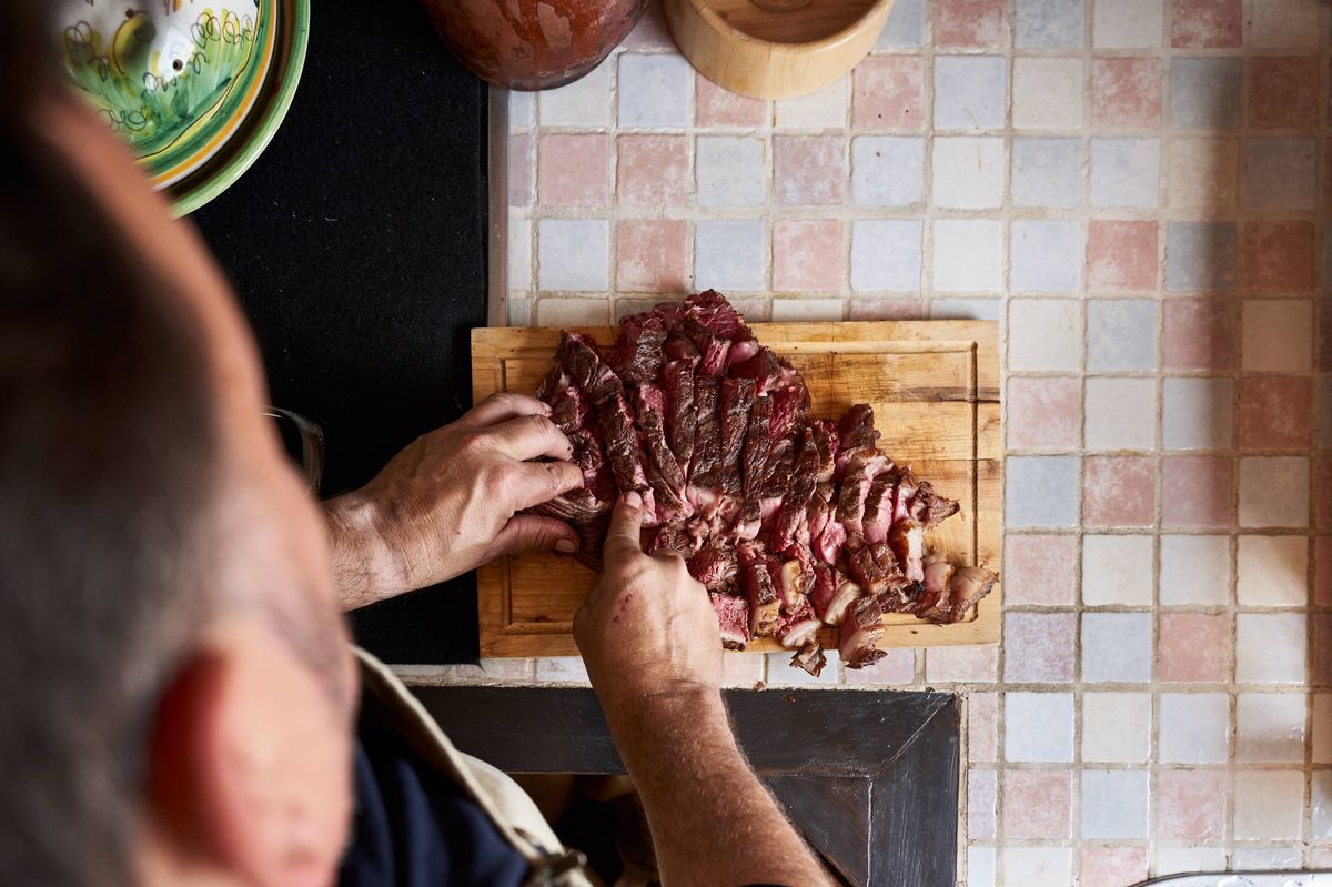 Close-Up Of high View of Man Preparing Tomakawk Steak On Cutting Board In A Kitchen. Horizontal photography.