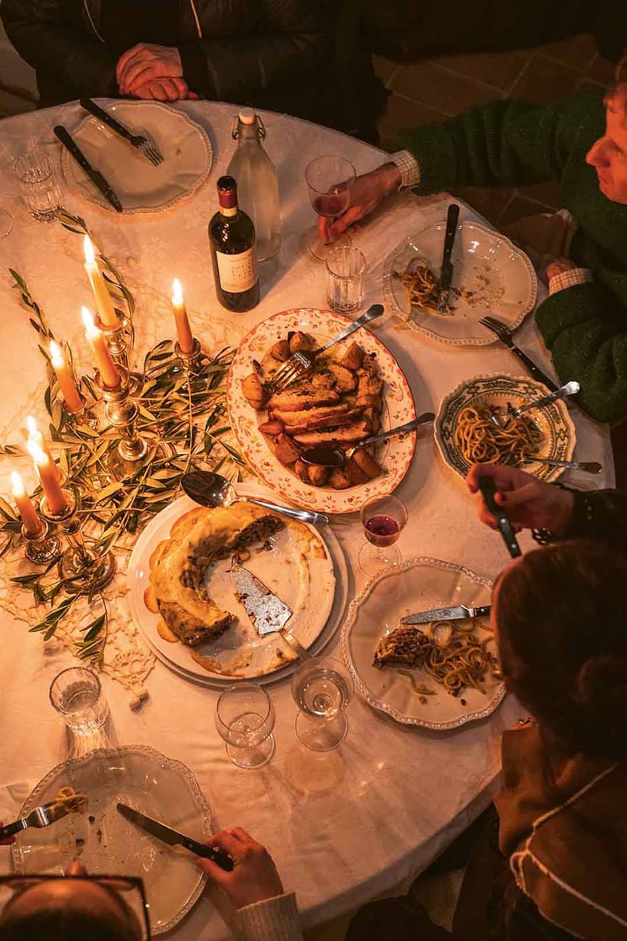 A dynamic shot of a lively and festively set dinner table from the birds-eye perspective, with diners sharing multiple plates of hearty food.
