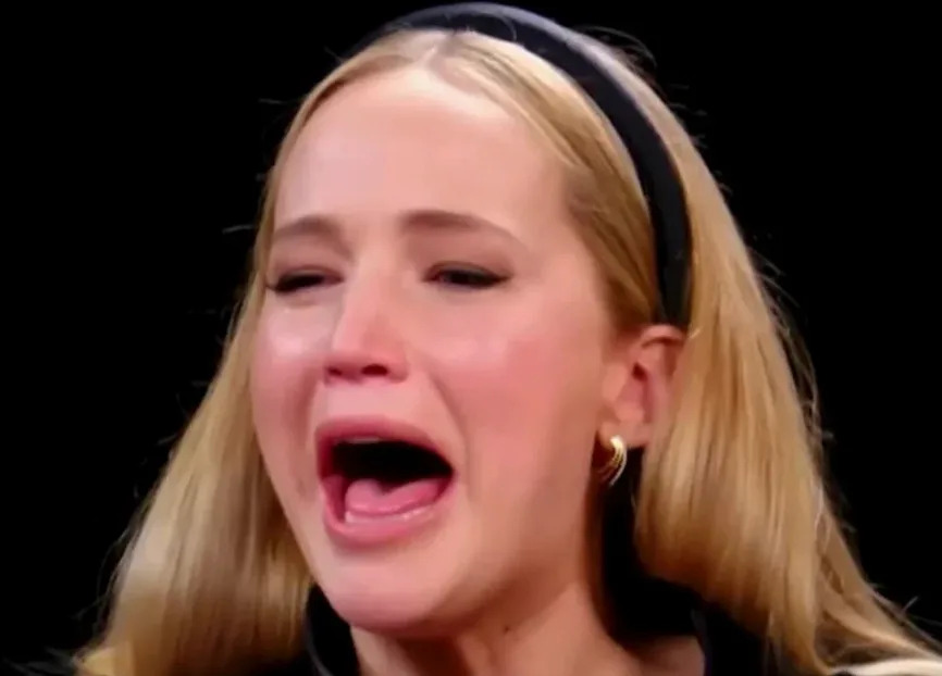 Person on a talk show reacts dramatically while discussing spicy food challenges