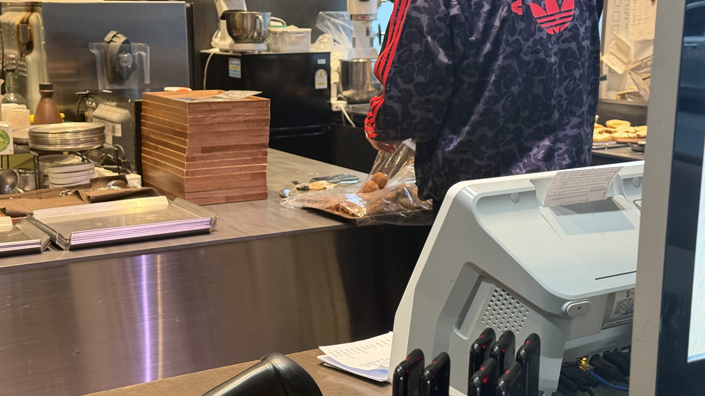 A bakery employee packages two Dubai chewy cookies from a tray kept behind a counter. [WOO JI-WON]
