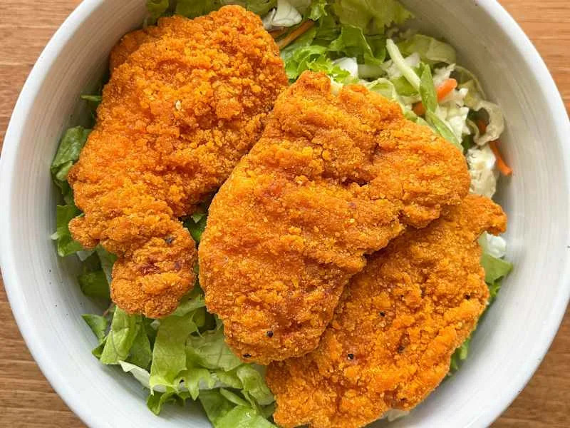 Applegate Natural Spicy Chicken Breast Tenders atop of greens.