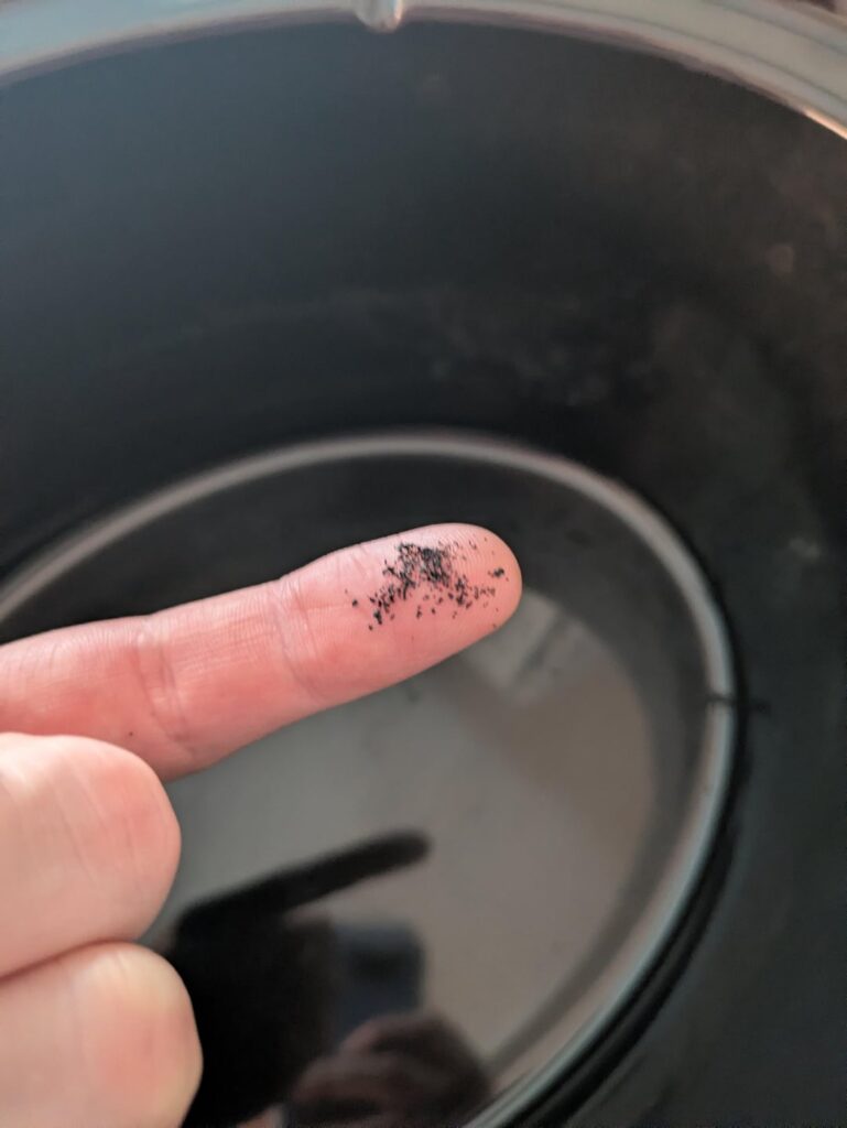 Crockpot scratched in the dishwasher, leaving behind black, glassy residue. Will it be safe to use after a thorough cleaning?