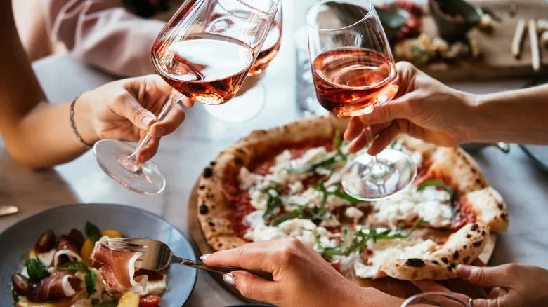 hands holding wine and picking at food
