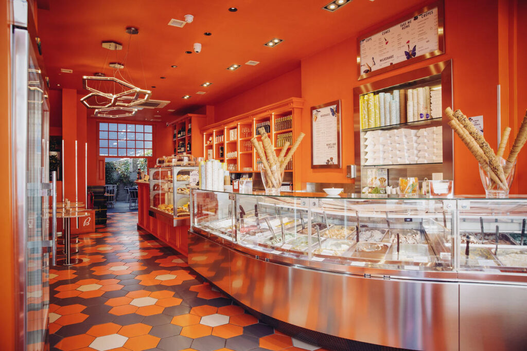 the bright orange interiors of a badiani gelato shop, with row after row of flavours visible at the counter