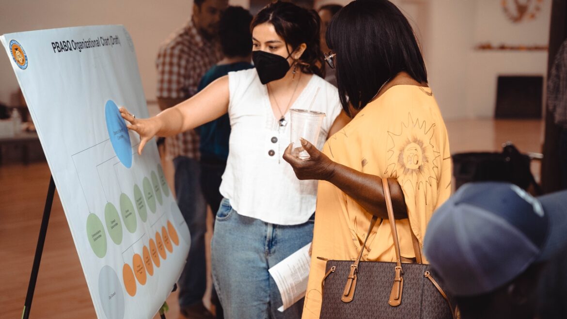 UNM students and faculty support budgeting and food justice efforts in District 6 UNM student Alicia Rodriguez lays out the organizational structure of PBABQ to a community member.