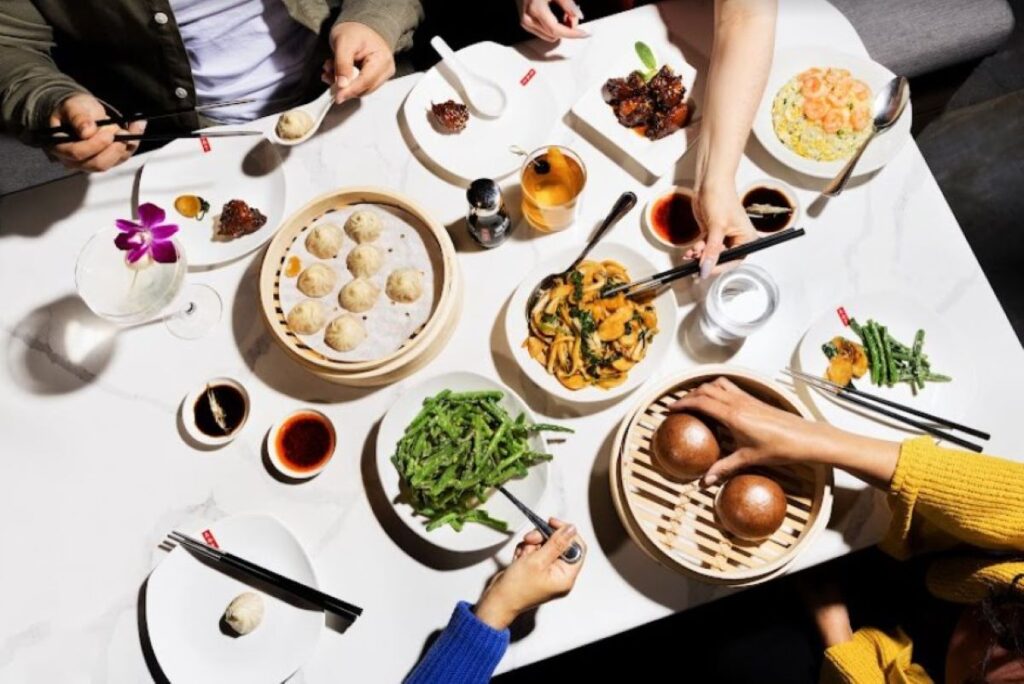 A group of people eats shareable dishes from Din Tai Fung.