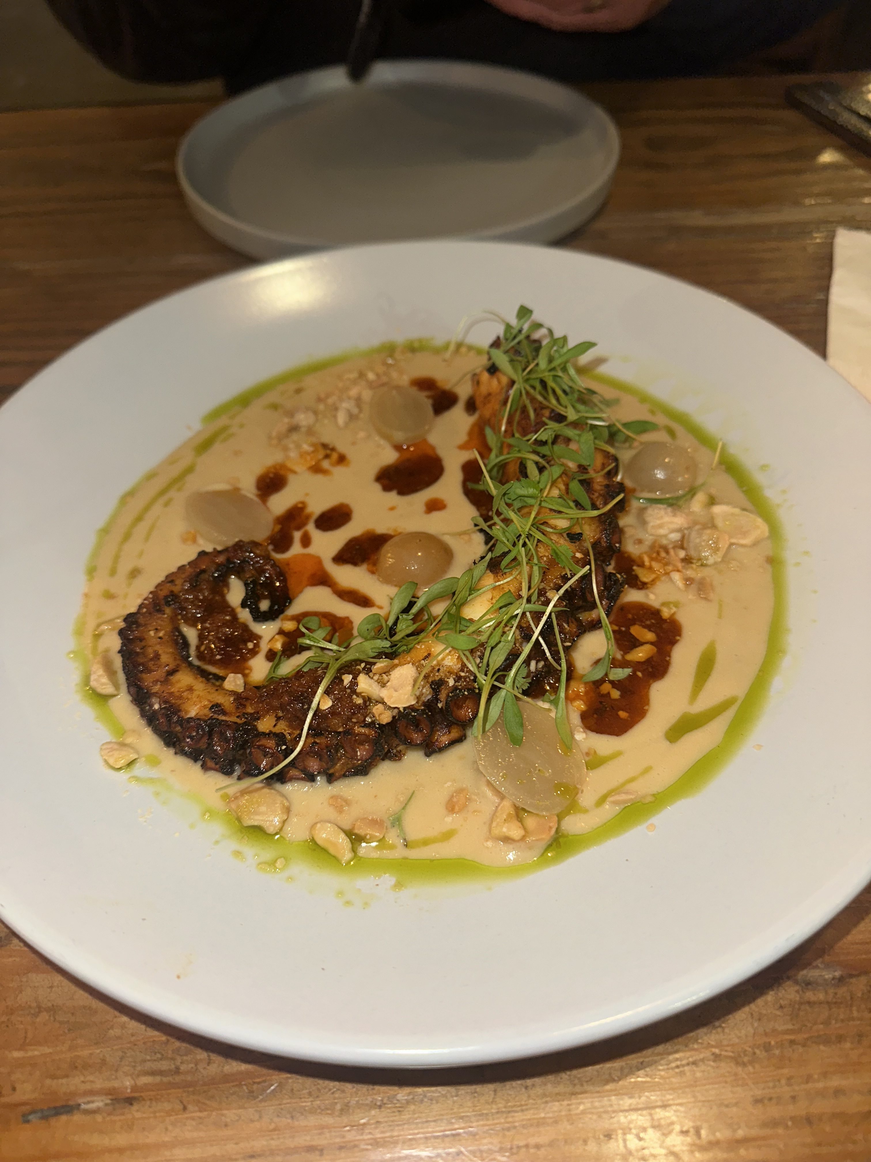 Charred pulpo (octopus) served with pickled grapes in a mole...