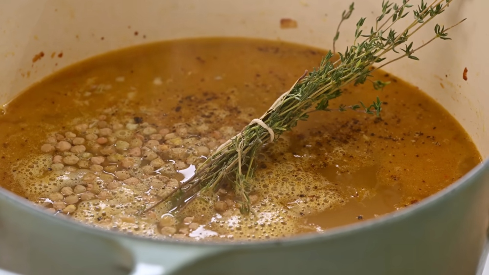 Bouquet garni infusing Mediterranean lentil soup with bay leaves and thyme during cooking