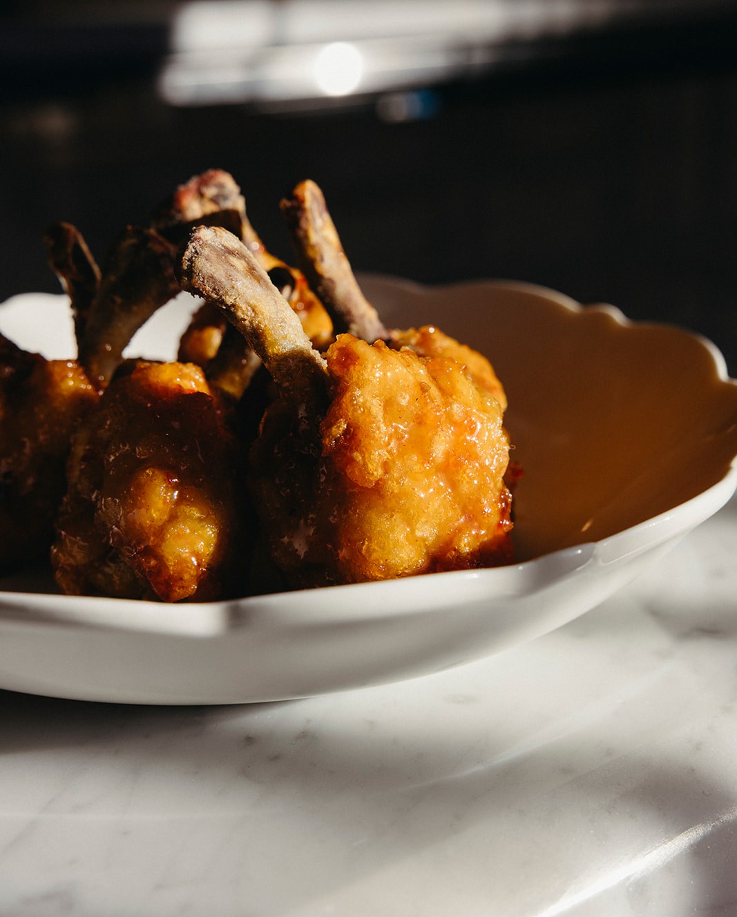 Fried chicken with lollipop drumsticks in a shallow white bowl at Lapaba.