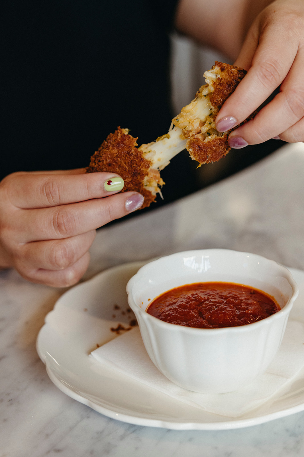 Hand pulling apart a fried suppli at Lapaba filled with kimchi and Spam.