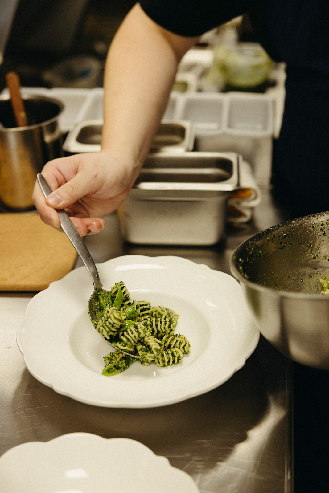 Hand with a spoon plating radiatore pasta with perilla basil at Lapaba.