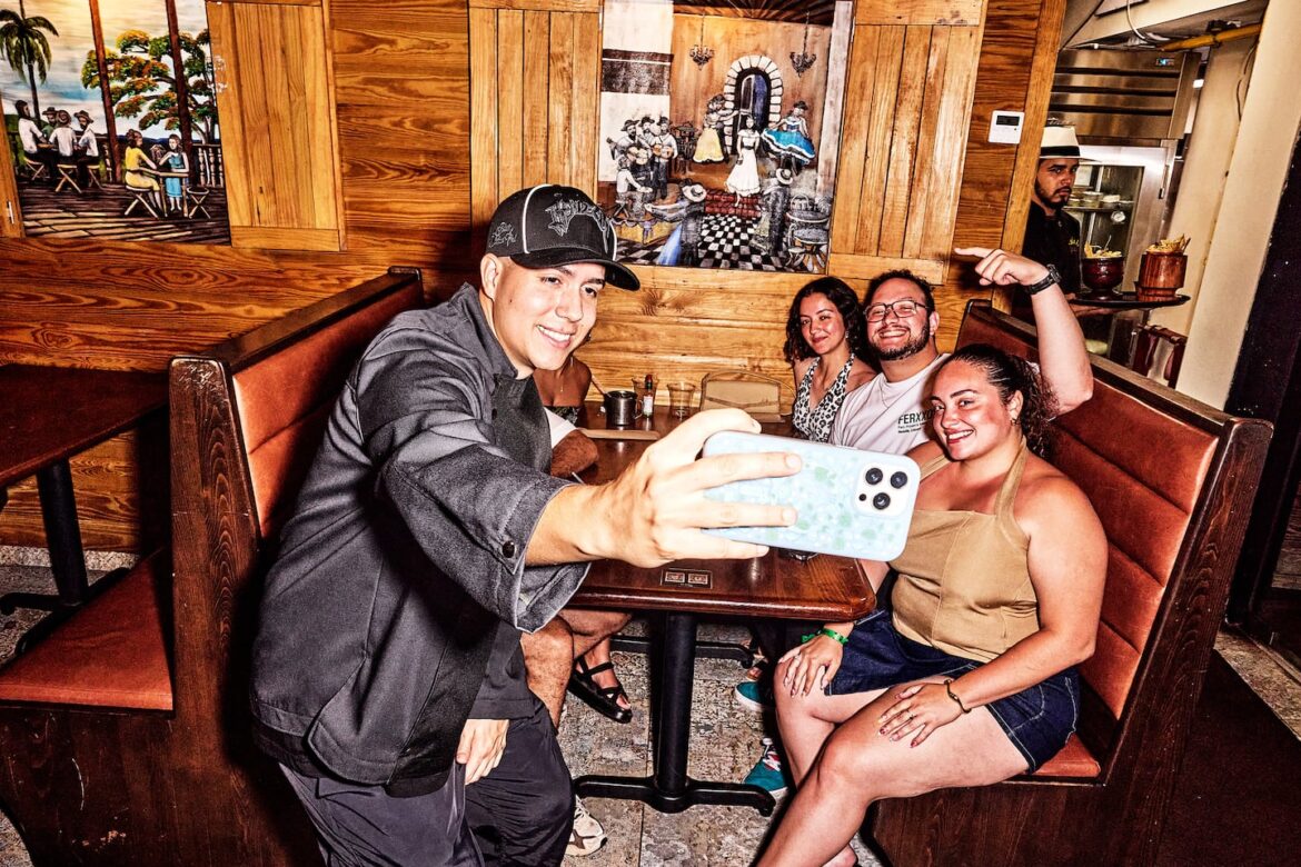 Ivn Mulero Ortiz, known as the Puerto Rican food influencer BoriLicious, takes a selfie with patrons.