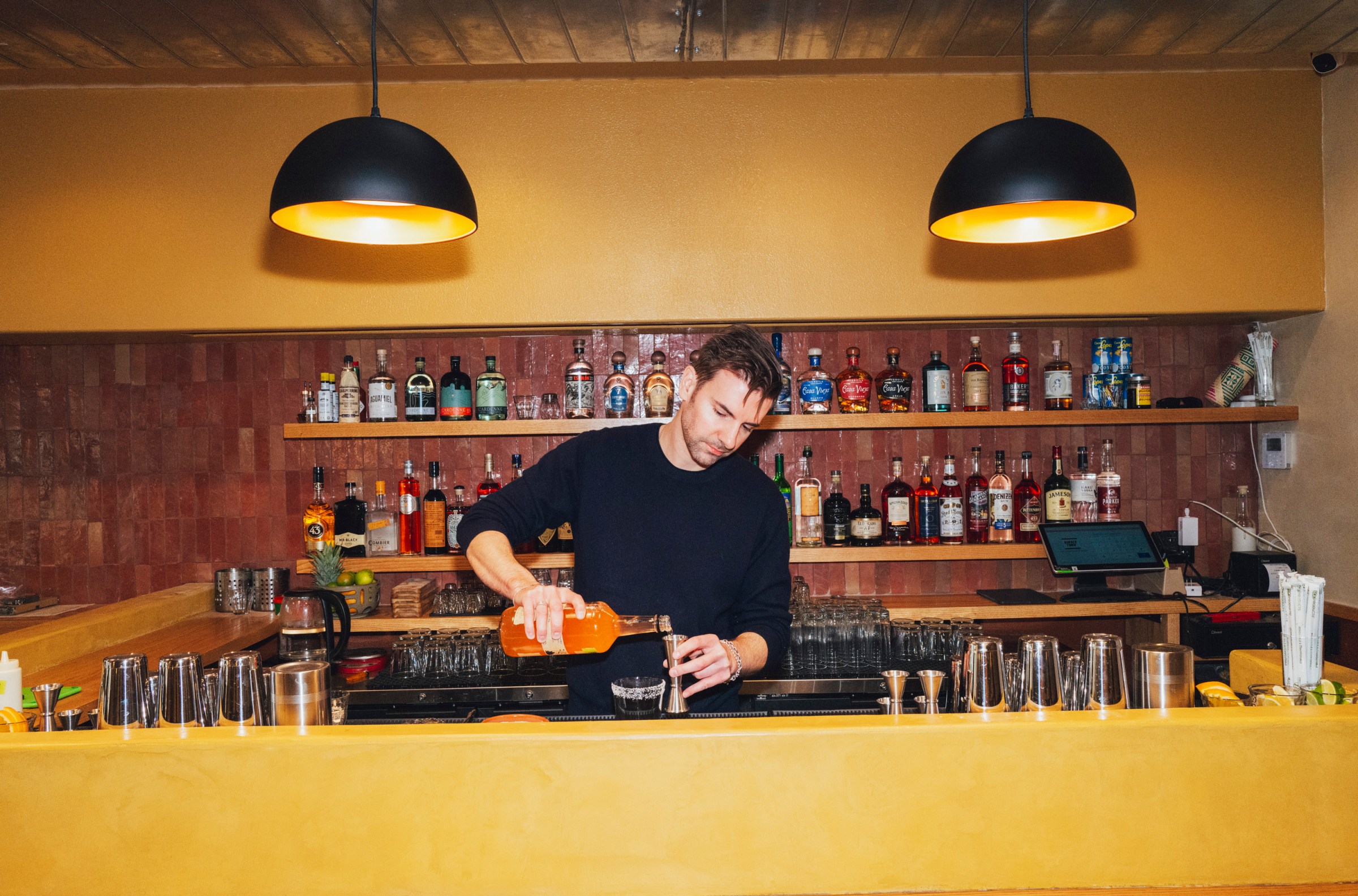 A person making a drink at a bar.