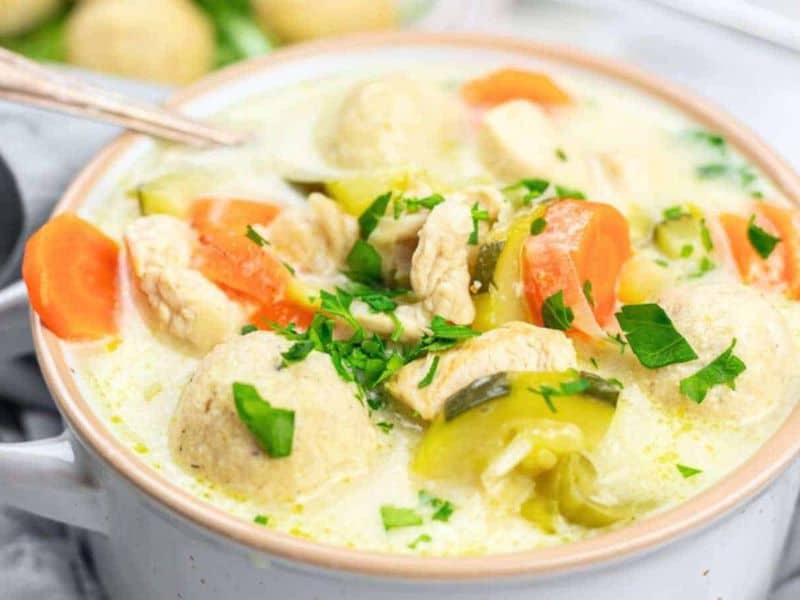 A bowl of creamy soup with chicken and dumplings.