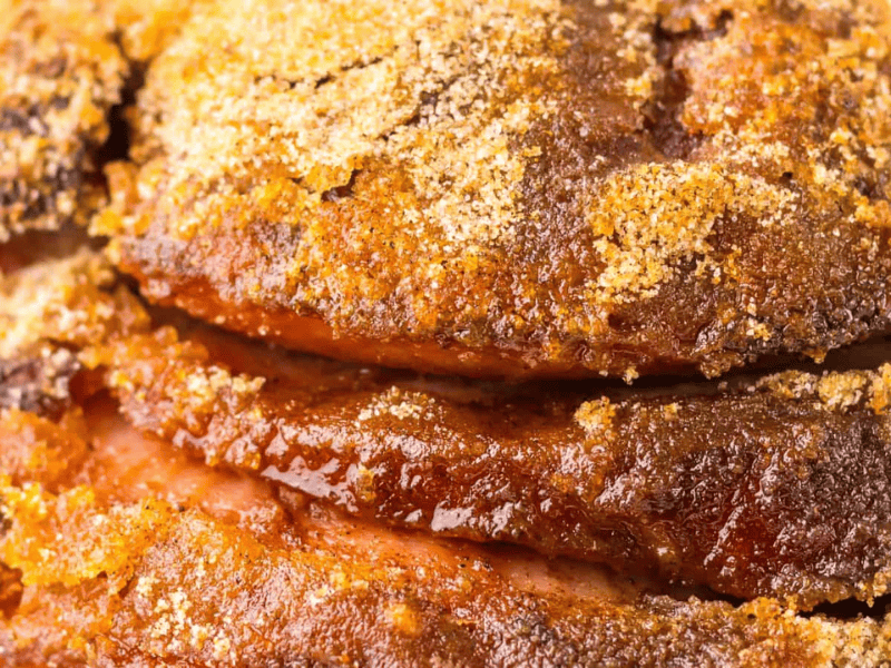Close-up of seasoned and roasted meat with crispy edges.