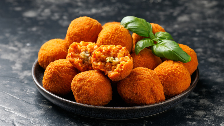 A plate of arancini with a sprig of basil