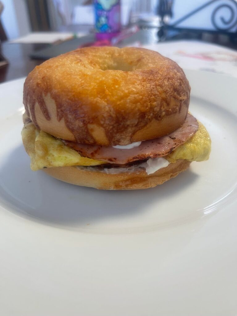 Eggs & fried ham on toasted Asiago bagel with onion/chive cream cheese