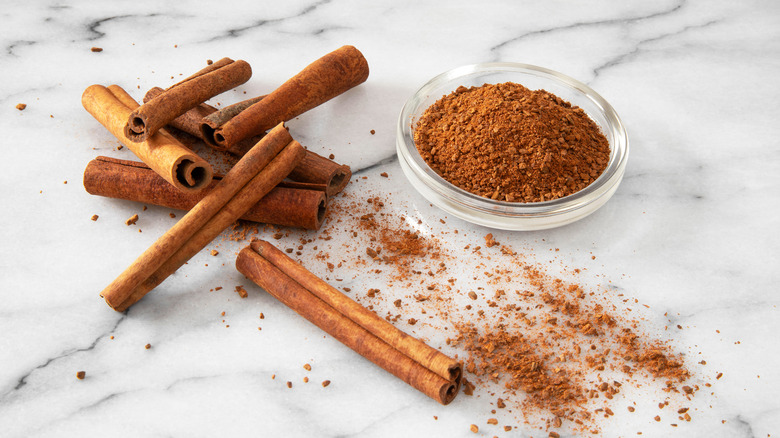 Close up of cinnamon sticks and powder in a glass bowl