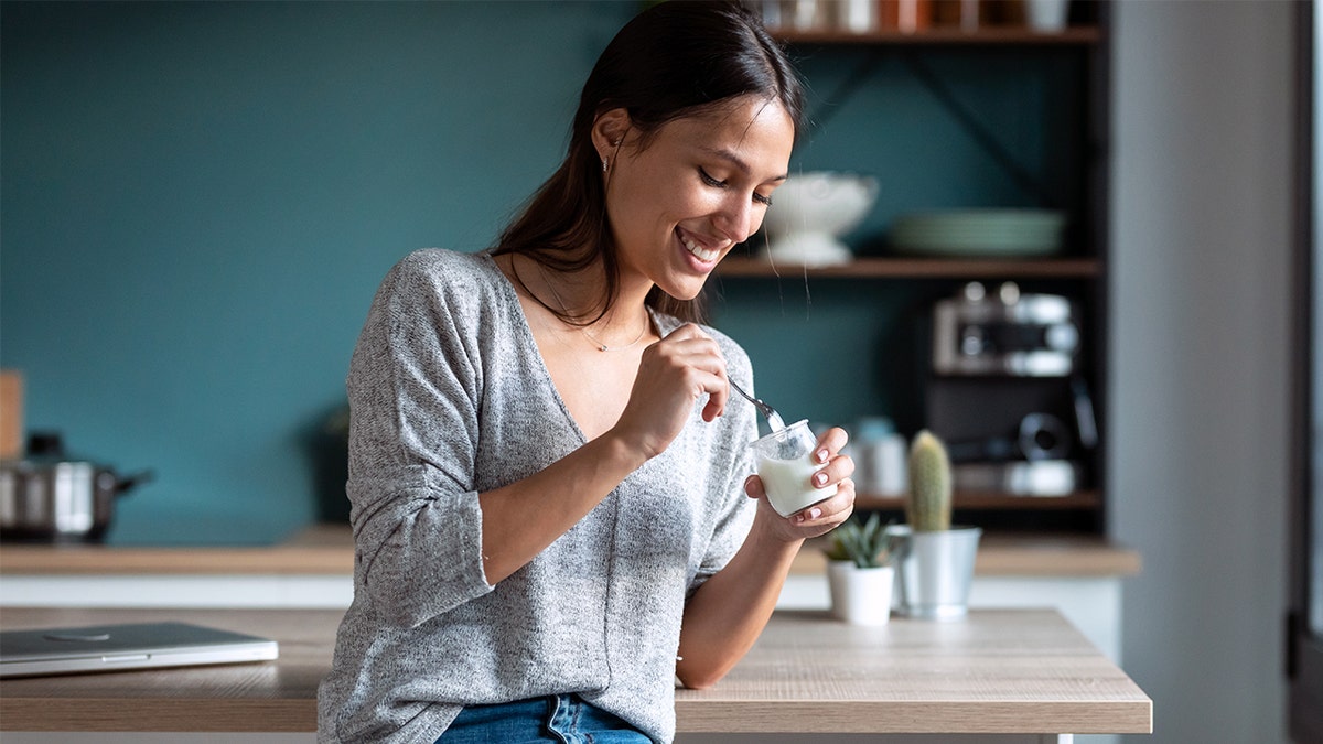 Younger woman smiling while eating yogurt