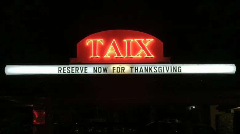 Red neon Taix sign glowing in the dark