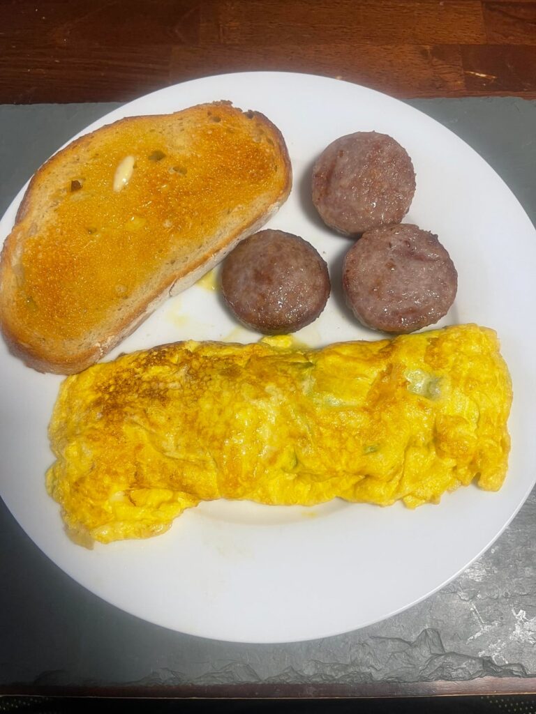 (Little overcooked) omelette loaded with spinach & some havarti cheese, breakfast sausage patties and a buttered/toasted sourdough slice