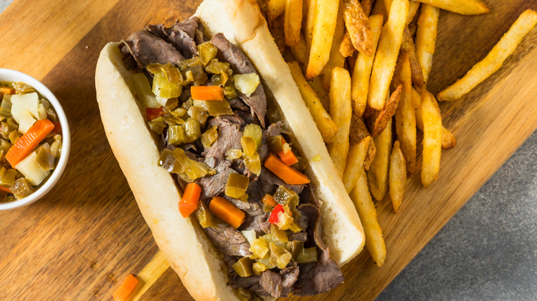 An overhead view of an Italian beef sandwich, served with giardiniera and french fries