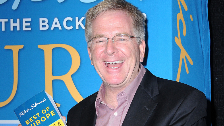 Rick Steves smiles for photo while holding his book, 
