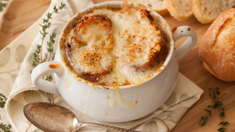 Crock of homemade French onion soup with crusty bread and fresh thyme