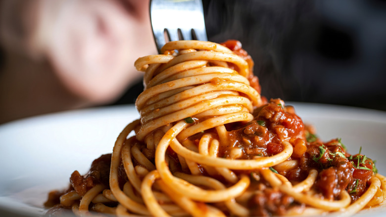 a fork twirls spaghetti bolognese