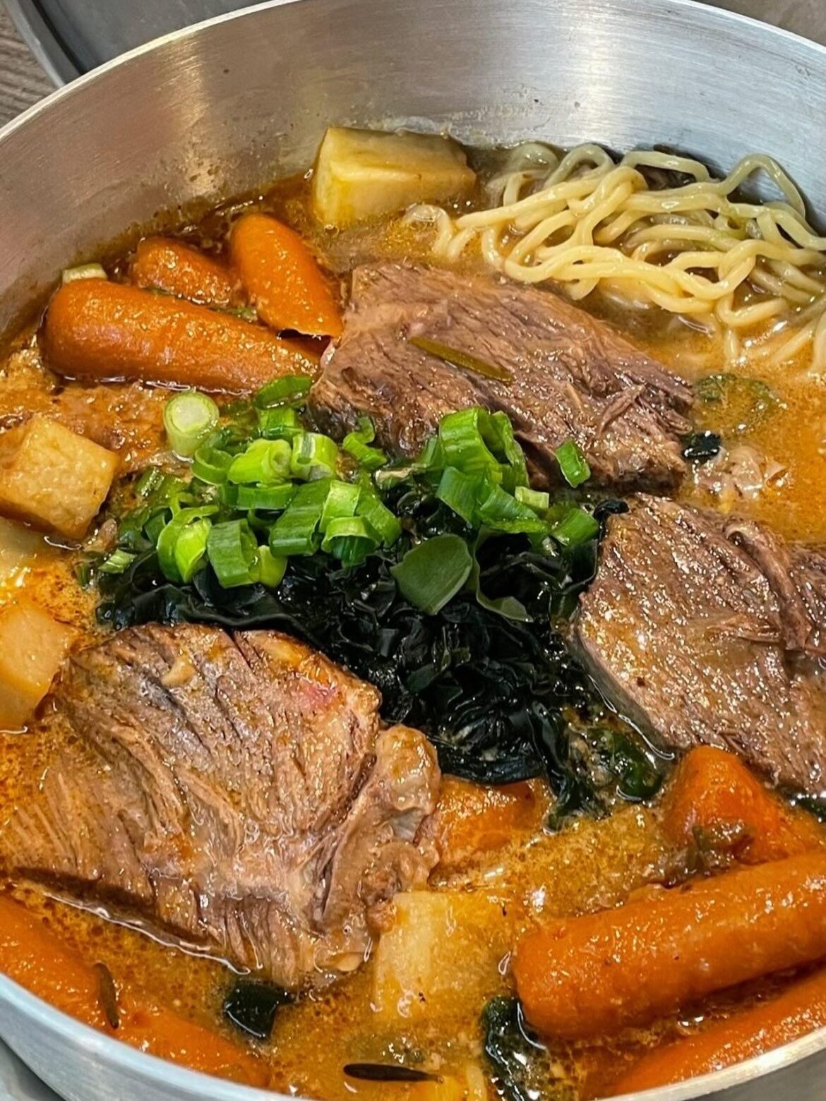 Slow-braised beef ramen with carrots, daikon, wakame, and spring onions in a rich, savory broth comfort in a bowl.