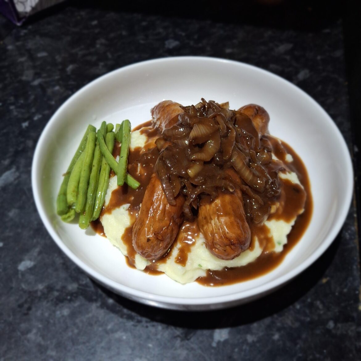 Pork bratwurst sausage, with mash, onions and gravy.