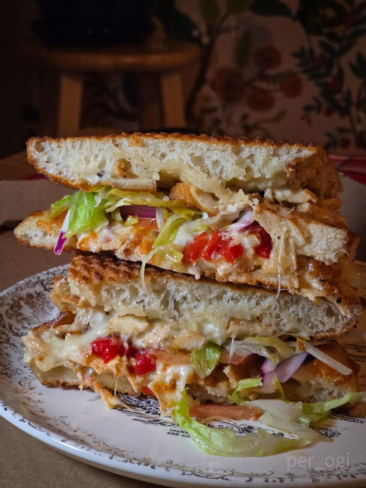 Pizza dough sandwich w/ sliced chicken breast, roasted red peppers, creamy feta, artichoke spread topped with cheese, seasoned lettuce, tomato, and red onion