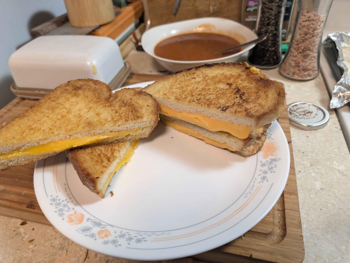 Sometimes the path to enlightenment is the one most trodden. Butter. White bread. Yellow american cheese. Tomato soup in background.