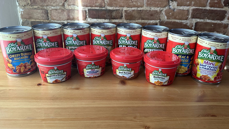 Chef Boyardee cans and cups on wooden table with brick background