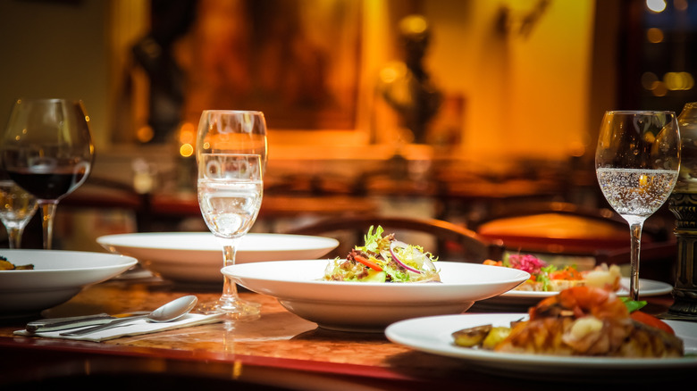 wine glasses and dishes of food on table in dimly lit restaurant