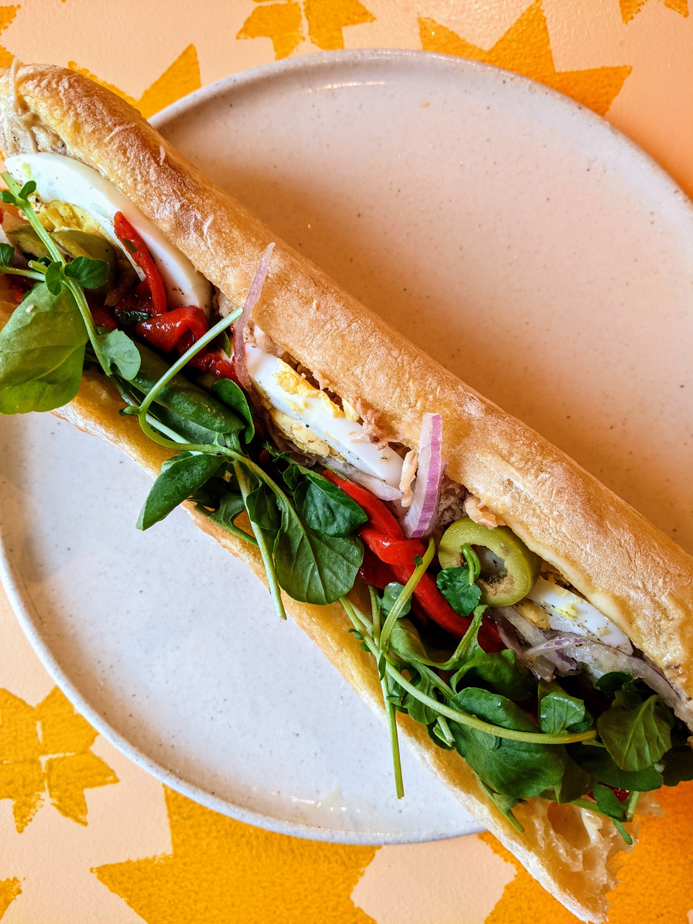 A baguette from Nido overflows with greens, hard-boiled egg, onions, peppers, and tuna.