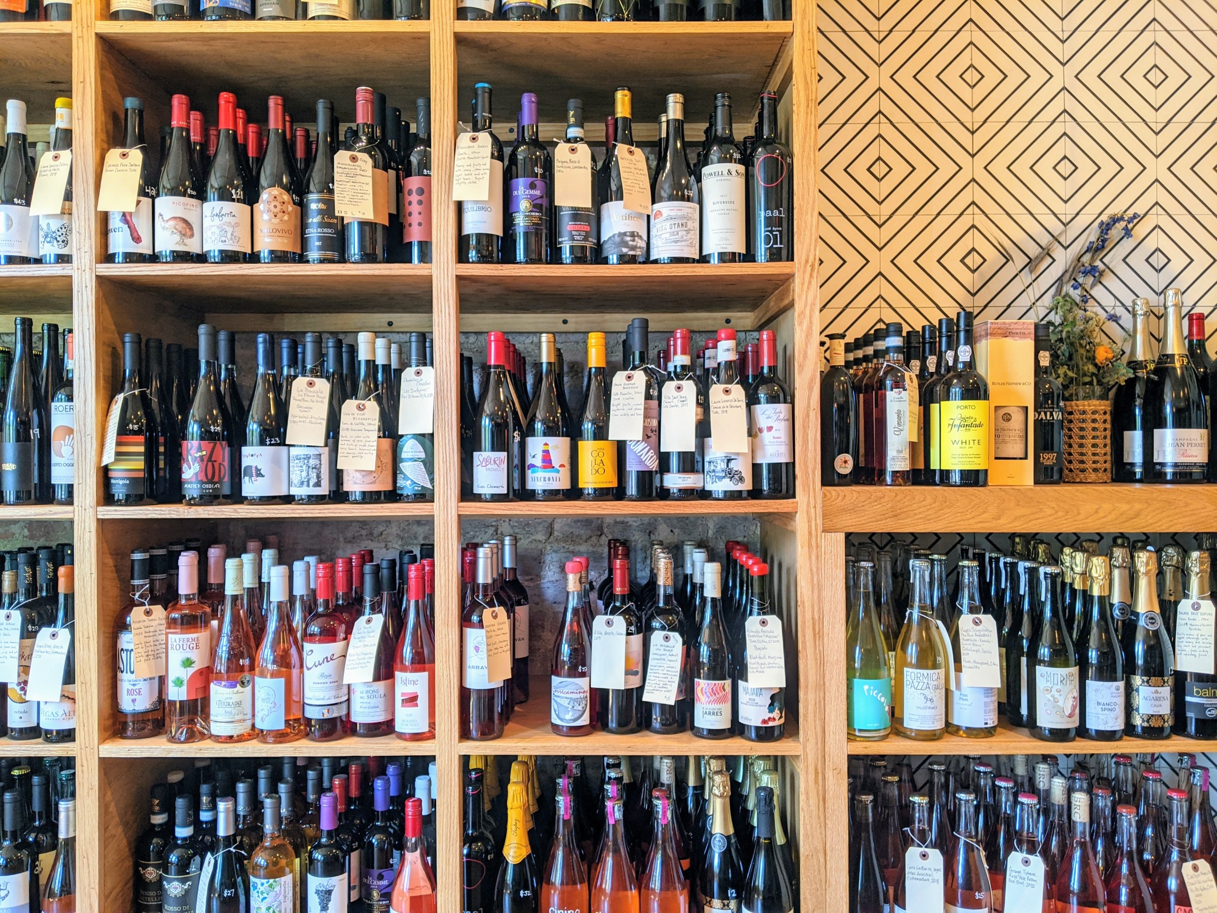Four rows of wooden shelves are fully stocked with wine bottles.