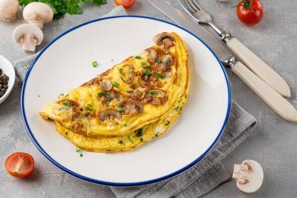 Omelet with fried mushrooms and fresh herbs in a plate on a concrete background. Delicious healthy breakfast. Top view. Copy spa